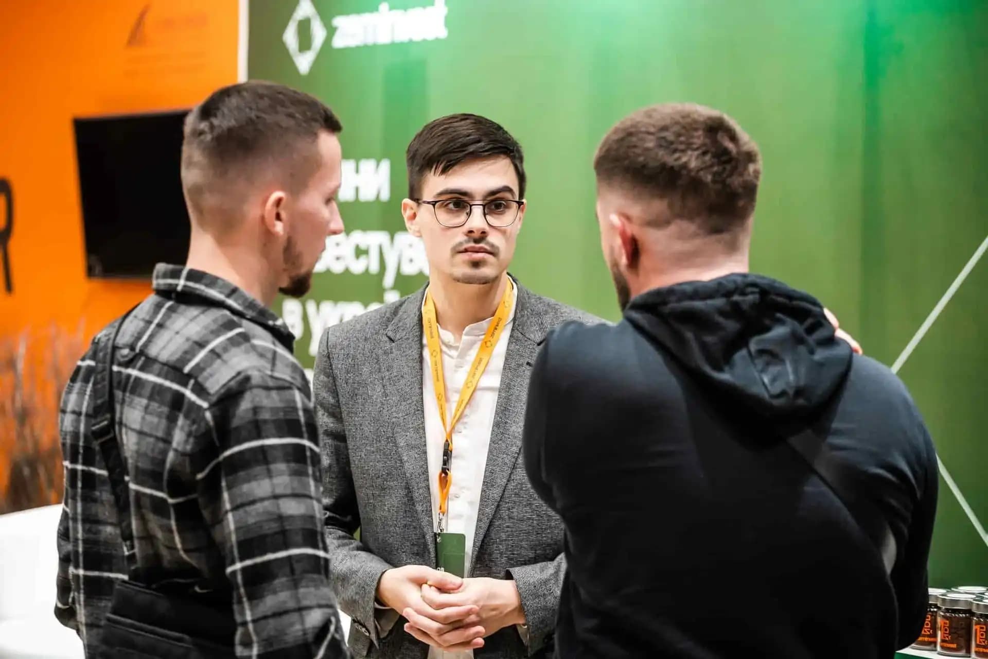 Three people having a conversation at an event with a "zeminvest" backdrop.